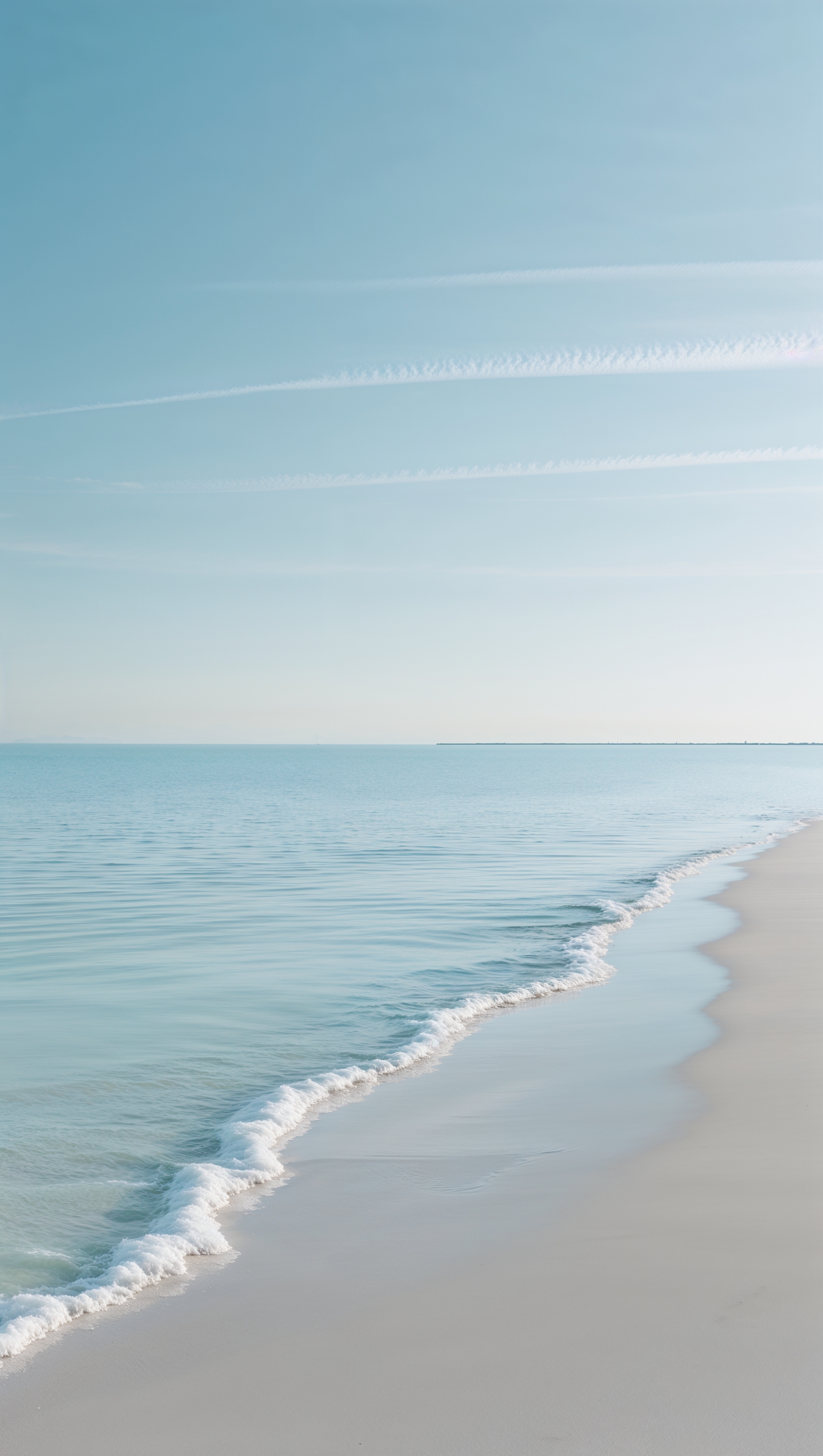Empty beach with light blue water and clear sky, minimalist aesthetic